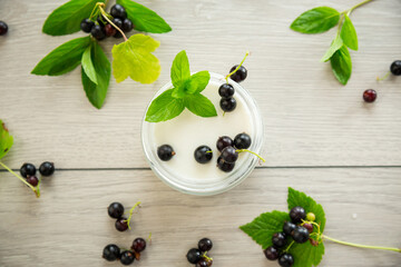 Poster - homemade sweet yogurt in a jar with black currants, on a wooden table