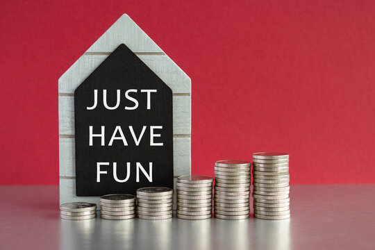 Just Have Fun symbol. Concept words Just Have Fun on a black board. Silver coins arranged in a graph in front. Beautiful red background, grey table. Inspiration quote.