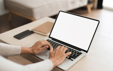 Wall Mural - Young woman holding a laptop with a blank white screen on the table. Work space in your home living room or home office