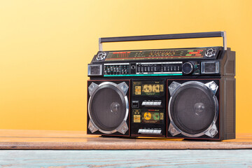 Wall Mural - boombox radio stereo cassette recorder on vintage oak table front yellow background. retro old style