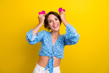 Sticker - Photo of playful carefree lady dressed flower print top holding pink hearts ears isolated yellow color background