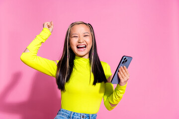 Wall Mural - Photo of overjoyed cute girl with dyed hairdo dressed yellow shirt holding smartphone win gambling isolated on pink color background