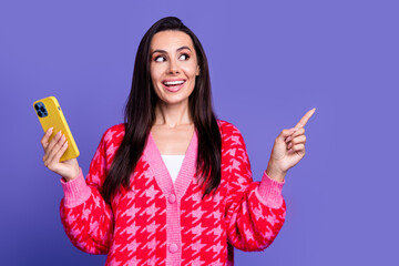 Canvas Print - Photo of shiny attractive lady dressed pink cardigan communicating modern device pointing emtpy space isolated violet color background