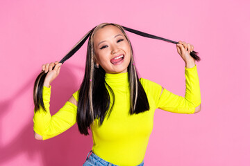 Wall Mural - Photo of positive girl with dyed hairstyle dressed yellow turtleneck hold curls tongue lick lips isolated on pink color background