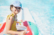 © Dasha Petrenko - Close-up of a little girl in a swimsuit and a cap with an inflatable circle. A cute child is smiling and swimming in the pool. A lovely kid is having fun in the clear water.