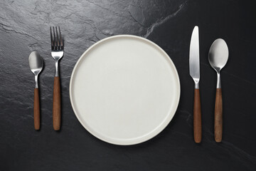 Wall Mural - Stylish cutlery and plate on black table, flat lay