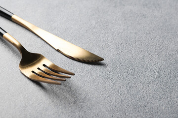 Wall Mural - Stylish golden cutlery on grey table, closeup. Space for text