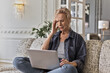 © Cavan Images - Senior woman has headache using laptop sitting on a couch