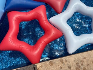 Sticker - Colorful star-shaped pool floats in blue water on a sunny day