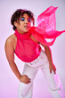 © LIGHTFIELD STUDIOS - A stylish African American woman posing actively in white pants and a pink top.