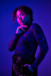© LIGHTFIELD STUDIOS - African American woman stands in dark room, hand on chin.