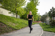 © zinkevych - Woman running on asphalt road in summer park active sporty female