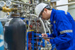 © reewungjunerr - Asian engineer working at Operating hall,Thailand people wear helmet  work,He worked with diligence and patience,she checked the valve regulator at the hydrogen tank.