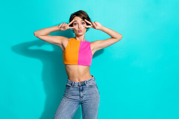 Wall Mural - Photo of excited flirty lady dressed colorful top showing two v-signs cover eyes empty space isolated turquoise color background