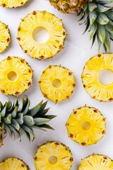 Canvas Print - Pina colada rings made from pineapple slices, arranged neatly on white background with pineapples in the background.