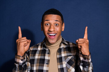 Wall Mural - Photo portrait of attractive young man point up empty space dressed stylish checkered clothes isolated on dark blue color background