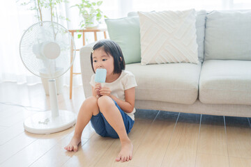 Wall Mural - 夏休みに扇風機の前でアイスを食べる子供