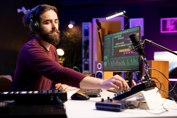 Fototapete - Professional sound engineer creating music on mixing console, twisting pre amp knobs and listening to the final soundtrack. Producer working in music industry post production, home studio.
