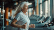 © Maksym - Radiant senior woman jogging on a treadmill, capturing the essence of fitness and happiness in her golden years, active elderly female pensioner exercising