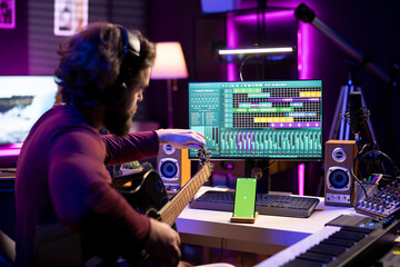 Leinwandbilder - Beginner artist learning strings accords to play guitar by watching tutorials and online lessons, smartphone shows greenscreen mockup. Singer practicing acoustic instrument skills in home studio.
