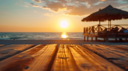 Aufkleber - A wooden table with a view of the ocean and a beach umbrella. The sun is setting in the background