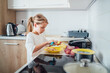 © Soloviova Liudmyla - Young girl concentrates on preparing potato dish in sleek modern kitchen. She cleaning potato with peeling knife cozy atmosphere, highlighting the joys of culinary creativity at home.