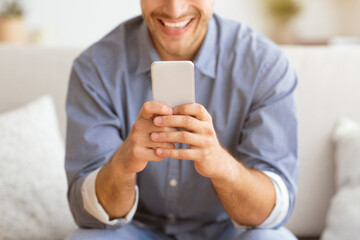 Poster - Happy Man Texting at Phone. Guy Playing On Smartphone Sitting On Sofa At Home