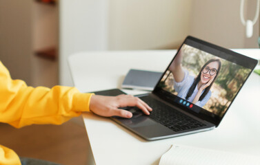 Poster - A person with a yellow shirt is sitting at a desk with a laptop computer. The laptop is open, and a video chat is taking place.