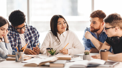Aufkleber - A diverse group of students sitting together at a table, engaged in conversation and possibly doing homework. Some are gesturing while speaking, while others are listening attentively