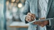 © LifeMedia - A person in business attire is using a digital tablet with a stylus in a modern and well-lit office setting, focused on a task or project.
