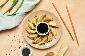 Wall Mural - Plate with tasty Chinese jiaozi, green onion and sauce on beige background