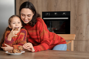 Canvas Print - Young mother and her little daughter eating tasty cookies in kitchen