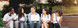 © Prostock-studio - Group Of Multi-Ethnic Students Sitting Outdoors With Laptop, Chatting And Preparring For Classes Together