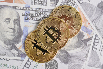 Golden symbolic coin Bitcoin on banknotes of one hundred dollars. Exchange bitcoin cash for a dollars. Cryptocurrency on US dollar bills. Savings, investments concept. Digital modern method of payment