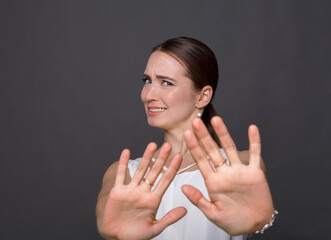 Attractive woman saying thanks but no. Beautiful girl denying proposal, making stop gesture with her hands, looking at camera