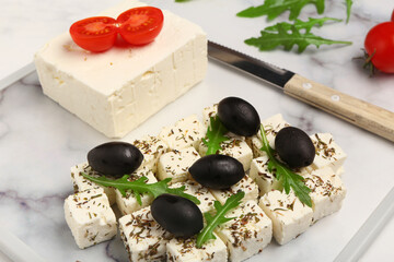 Poster - Board with delicious cut feta cheese, black olives and tomatoes on white grunge background