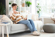 © Pixel-Shot - Male student with laptop studying online on sofa at home