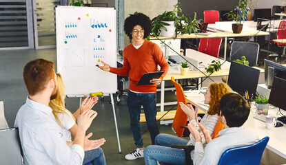 Wall Mural - Male office worker giving creative presentation to his colleagues, explaining business plan to coworkers in coworking office, free space