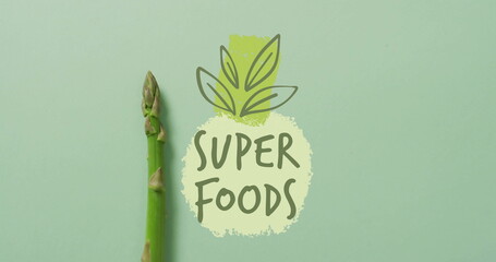 Wall Mural - Asparagus spear with SUPER FOODS text and leaf image on green background