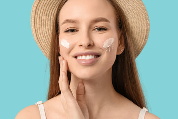 Sticker - Beautiful young happy woman with sunscreen cream on her face against blue background