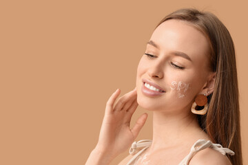 Sticker - Beautiful young happy woman with sunscreen cream on her face against beige background