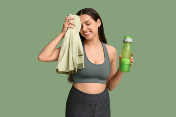 Poster - Beautiful young happy woman with towel and sports bottle of water on green background