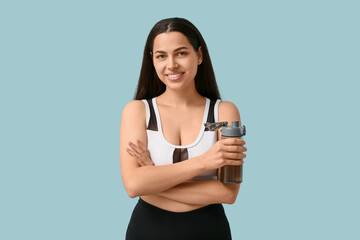 Poster - Beautiful young happy woman with sports bottle of water on blue background