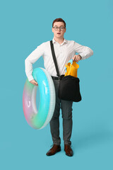 Canvas Print - Office worker with inflatable ring and flippers in bag dreaming about vacation on blue background