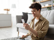© Prostock-studio - Testing New App. Handsome Asian Man Using Smartphone While Relaxing Leaning On Couch At Home, Happy Guy Sitting On Floor In Living Room, Browsing Internet Or Messaging With Friends, Free Copy Space
