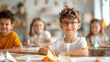 © LifeMedia - A young boy with glasses smiles confidently while seated at a classroom desk with classmates in the background, showcasing a lively and inclusive learning environment.