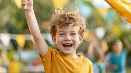 A joyful child dressed in a yellow shirt holds up a finger in celebration with vibrant flags and other children in an outdoor setting. Displaying a sense of triumph and happiness.