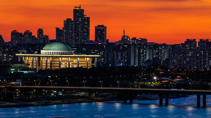 Wall Mural - Yeouido, Yeongdeungpo-gu, Seoul, South Korea - September 26, 2018: Sunset and night view of Sogang Bridge on Han River with National Assembly and apartments against red sky
