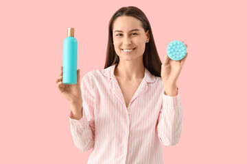 Sticker - Beautiful young happy woman with bottle of shampoo and hair scalp massager on pink background