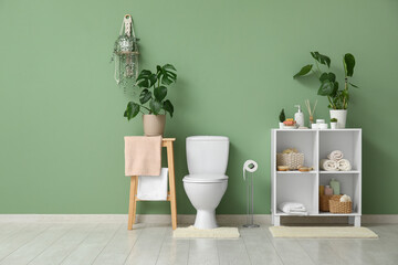 Poster - Toilet bowl and shelving units near green wall in restroom